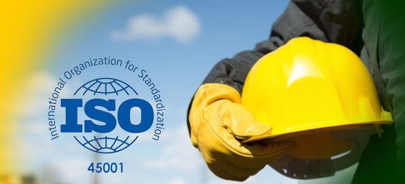 Φωτογραφία ενός εργάτη (δε φαίνεται το πρόσωπό του), που κρατάει μια κάσκα ασφαλείας κίτρινη, και δίπλα στον άδειο χώρο της φωτογραφίας αποτυπώνεται το λογότυπο του ISO 45001.